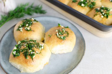 Sarımsaklı üç çörek ve gri tabakta yağlı dereotu sosu. Borç için geleneksel Ukrayna çörekleri olan pampushky (Pampushky) hazırlığı. Geleneksel yemek kavramı. Ev yapımı pişirme..