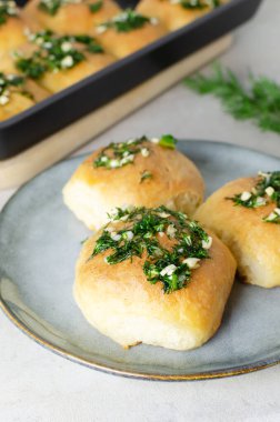 Sarımsaklı üç çörek ve gri tabakta yağlı dereotu sosu. Borç için geleneksel Ukrayna çörekleri olan pampushky (Pampushky) hazırlığı. Geleneksel yemek kavramı. Ev yapımı pişirme..