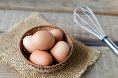 Hasır bir kasede tavuk yumurtası, ahşap bir arka planda çuval beziyle çırpılmış. Kırsal tarzda. Organik gıda kavramı. Yatay yönelim.