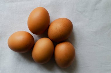 Beyaz masa örtüsü üzerinde bir sürü tavuk yumurtası. Kırsal tarzda. Organik gıda kavramı. Minimalizm. Yatay oryantasyon. Uzayı kopyala Üst görünüm