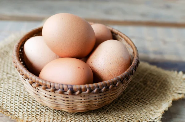 stock image Chicken eggs in a wicker bowl on burlap on a wooden background. Rustic style. The concept of organic food. Horizontal orientation.