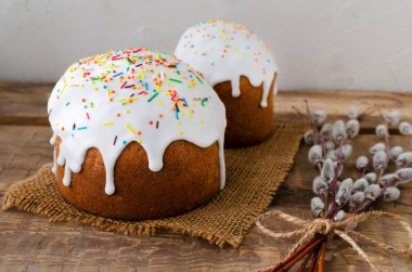 Tahta arka planda söğüt tomurcukları olan çuval bezli iki geleneksel Ukraynalı kulich. Bayramlık Paskalya pastası konsepti. Kırsal tarzda. Seçici odaklanma. Yatay yönelim.