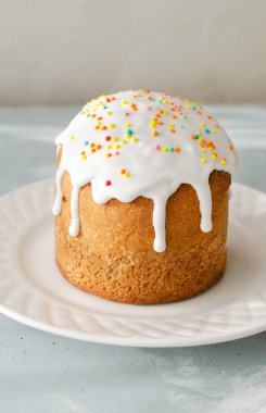 Geleneksel Ukrayna Kulich 'i gri arka planda beyaz bir tabakta. Bayramlık Paskalya pastası konsepti. Seçici odaklanma. Dikey yönelim.