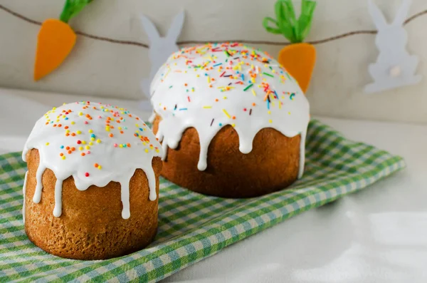 İki geleneksel Ukraynalı kulich yeşil bir havluyla beyaz bir masa örtüsü üzerinde. Bayramlık Paskalya pastası konsepti. Seçici odaklanma. Yatay yönelim.