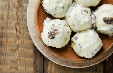 Tavukla doldurulmuş hamur köfteleri beyaz mantar ve ahşap bir zemindeki kil tabakta dereotu sosu. Geleneksel Ukrayna mutfağı kavramı. Üst Manzara. Yatay oryantasyon. Boşluğu kopyala