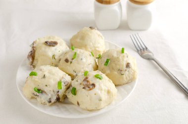 Beyaz mantarla doldurulmuş tavukla doldurulmuş hamur tatlısı ve çatallı beyaz bir tabakta dereotu sosu. Geleneksel Ukrayna mutfağı kavramı. Yatay oryantasyon. Seçici odak.