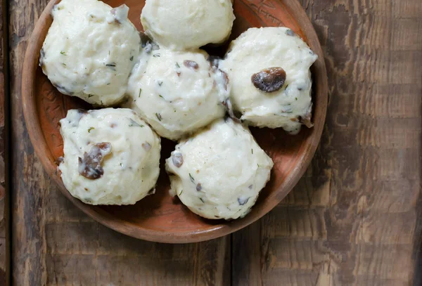 stock image Dumplings stuffed with chicken filling with white mushroom and dill sauce on a clay plate on a wooden background. Concept Traditional Ukrainian cuisine. Top view. Horizontal orientation.