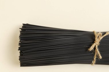 Sarı arka planda mürekkep balığı mürekkebi olan bir demet çiğ siyah spagetti. Sağlıklı gıda kavramı. Yatay oryantasyon. Seçici odaklanma. Üst Manzara. Boşluğu kopyala.