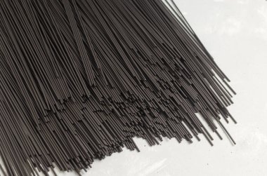 Gri arka planda mürekkep balığı mürekkebi olan bir demet çiğ siyah spagetti. Sağlıklı İtalyan yemeği kavramı. Yatay oryantasyon. Seçici odak.