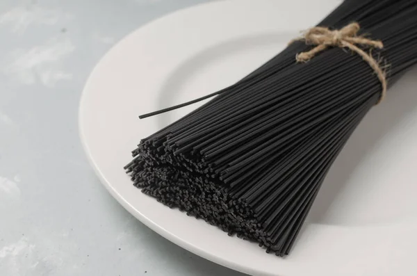 Hromada Syrových Černých Špaget Sépiovým Inkoustem Bílém Talíři Šedém Pozadí — Stock fotografie