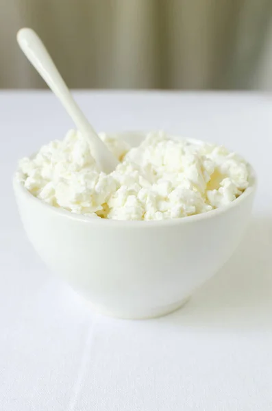 白いテーブルクロスの上に白いセラミックボウルにオーガニックコテージチーズ 健康的な朝食 自家製食品の概念 選択的フォーカス 垂直方向 — ストック写真