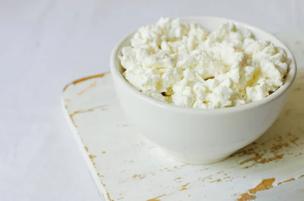 白いテーブルクロスのライトカットボード上の白いセラミックボウルに有機コテージチーズ 健康的な朝食 健康食品の概念 選択的フォーカス 水平方向 スペースのコピー — ストック写真