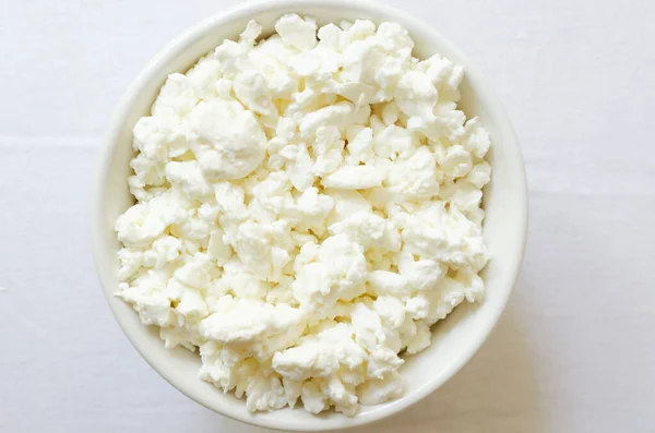白いテーブルクロスの上に白いセラミックボウルにオーガニックコテージチーズ 健康的な朝食 健康食品の概念 選択的フォーカス 水平方向 最上階だ コピースペース — ストック写真