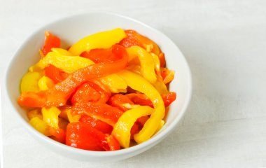 Gri bir seramik kasede büyük kırmızı ve sarı kavrulmuş biber dilimleri. Geleneksel İtalyan yemeği kavramı. Vejetaryen ve vejetaryen yemekleri. Yatay oryantasyon. Boşluğu kopyala.