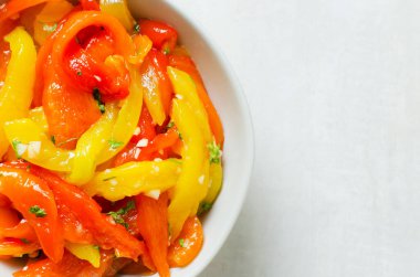 Gri bir seramik kasede dilimlenmiş kırmızı ve sarı kavrulmuş biberler. Sağlıklı beslenme kavramı. Geleneksel İtalyan yemeği. Vejetaryen ve vejetaryen yemekleri. Dikey oryantasyon. Üst Manzara. Boşluğu kopyala