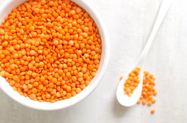 Beyaz kasede turuncu mercimek ve arka planda çay kaşığı. Düzgün beslenme kavramı. Vejetaryen ve vejetaryen yemekleri. Yatay oryantasyon. Üst görünüm.