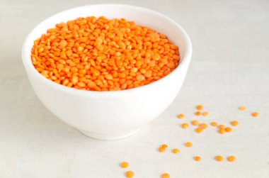 Arka planda beyaz bir kasede turuncu mercimek. Düzgün beslenme kavramı. Vejetaryen ve vejetaryen yemekleri. Yatay oryantasyon. Boşluğu kopyala.