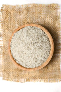 Çuval bezinde ahşap bir kasede çiğ basmati pilavı. Su tasarrufu ürünleri kavramı. Su tasarrufu. Dikey oryantasyon. Üst görünüm.