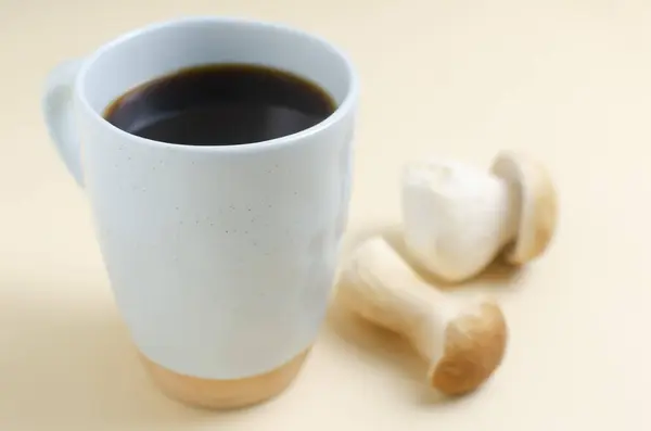 Mushroom coffee in a blue cup with mushrooms on a yellow background. The concept of a trendy beverage. The drink is good for health. Horizontal orientation. Selective focus.