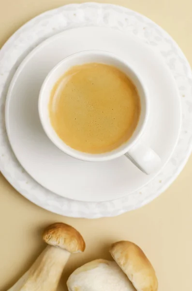 Mushroom coffee in a white cup with a saucer on a yellow background. The concept of a trendy beverage. The drink is good for health. Vertical orientation. Selective focus. Top view