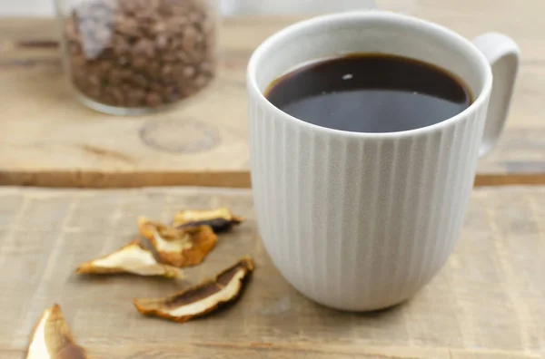 Mushroom coffee in a gray cup on a wooden background. The concept of a trendy beverage. The drink is good for health. Horizontal orientation. Selective focus. Copy space.
