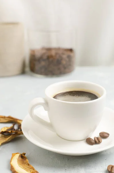 Mushroom coffee in a white cup and saucer with dried mushrooms and coffee beans. The concept of a trendy beverage. The drink is good for health. Vertical orientation. Selective focus