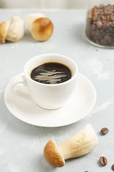Mushroom coffee in a white cup and saucer with dried mushrooms and coffee beans. The concept of a trendy beverage. The drink is good for health. Vertical orientation. Selective focus