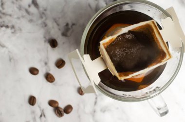 Gri mermer arka planda şeffaf bir fincana damlatılmış kahve yapma süreci. Lezzetli ve aromatik bir içki hazırlamanın hızlı bir yolu. Yatay oryantasyon. Seçici odaklanma. Üst görünüm