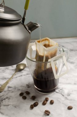 Gri mermer arka planda şeffaf bir fincana damlatılmış kahve yapma süreci. Lezzetli ve aromatik bir içki hazırlamanın hızlı bir yolu. Dikey oryantasyon. Seçici odak