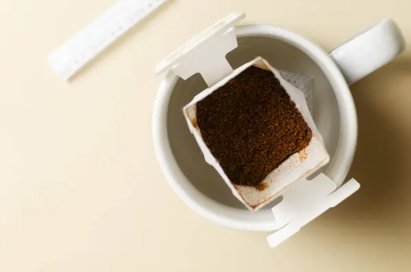 Drip coffee bag in a cup on a yellow background. A quick way to prepare a tasty and aromatic drink. Horizontal orientation. Top view. Copy space