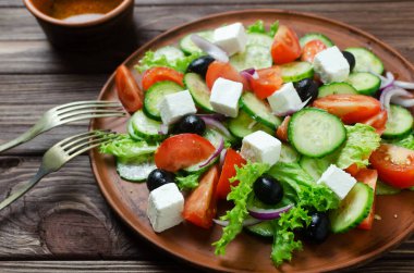 Salatalıklı, domatesli, kırmızı soğanlı, feta peynirli, marullu ve siyah zeytinli klasik Yunan salatası. Geleneksel yemek kavramı. Patronluk taslamak. Basit malzemeler. Üst görünüm.