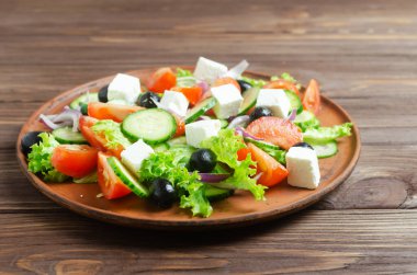 Salatalıklı, domatesli, kırmızı soğanlı, feta peynirli, marullu ve siyah zeytinli klasik Yunan salatası. Geleneksel yemek kavramı. Patronluk taslamak. Basit malzemeler. Üst görünüm.