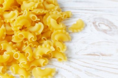 Çiğ Creste Di Gallo makarnası beyaz bir tahta yığınına saçılmış. Horoz tarağı. Geleneksel İtalyan yemeği kavramı. Yatay oryantasyon. Uzayı kopyala Seçici odaklanma. Üst görünüm