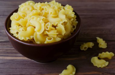 Kahverengi ahşap bir tahtanın üzerinde seramik bir kasede çiğ Creste Di Gallo pastası. Horoz tarağı. Geleneksel İtalyan mutfağı kavramı. Yatay oryantasyon. Seçici odak