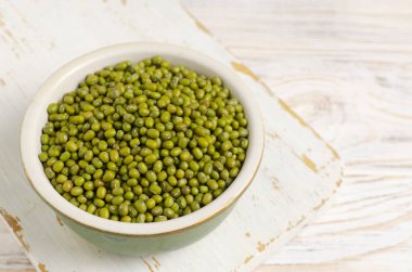 Beyaz ahşap arka planda seramik bir kasede yeşil fasulye. Organik baklagiller. Vejetaryen ve vejetaryen yemekleri. Sağlıklı beslenme kavramı. Yatay oryantasyon. Uzayı kopyala Seçici odak.