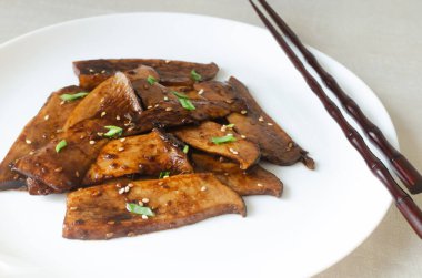 Beyaz tabakta susamlı ve yeşil soğanlı eryngii mantarı. Gochujang Kral İstiridye Mantarı pişirme süreci. Geleneksel Kore mutfağı kavramı. Yatay yönelim.