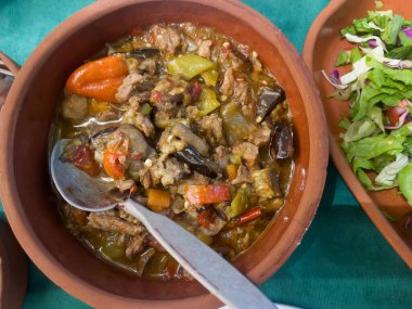 Patlıcanlı kuzu yahnisi ve öğle yemeği sırasında masada seramik kaselerde salata ve yeşil biber. Ev yapımı yemekler. Geleneksel Türk mutfağı kavramı. Yatay oryantasyon. Üst görünüm