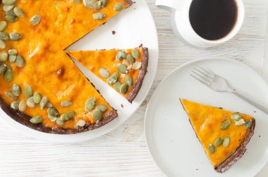 Beyaz tepside kurutulmuş çekirdekli portakallı kabak turtası ve masada bir fincan çay. Sonbahar havası. Çay saati konsepti. Yatay oryantasyon. Üst görünüm.