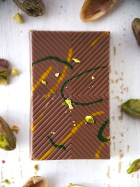 Fıstık ezmeli Dubai çikolatası ve şam fıstıklı süt. Popüler gıda konsepti. Dikey oryantasyon. Üst Manzara. Makro fotoğrafçılık