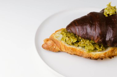 Fıstık ezmesiyle doldurulmuş kruvasan ve beyaz bir tabağa siyah çikolata serpiştirilmiş kadaif hamuru. Moda yemek konsepti. Uzayı kopyala Seçici odaklanma. Pankart