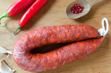 İspanyol Chorizo sosisi, kırmızı biber, kırmızı biber ve sarımsaklı tahta kesme tahtasının üzerinde bıçak ve malzemelerle. Geleneksel Akdeniz gıda konsepti. Yatay oryantasyon. Seçici odak.