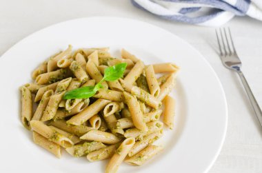 Fındık ezmeli makarna. Masada çatal ve beyaz bir tabakta fesleğen var. İtalyan mutfağı konsepti. Yatay oryantasyon. Seçici odak.