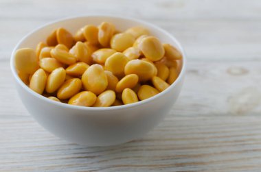 Ahşap bir masada beyaz bir kasede Lupin fasulyesi. İtalyan yemeği. Baklagiller. Sağlıklı gıda konsepti. Yatay oryantasyon. Seçici odaklanma. Boşluğu kopyala.