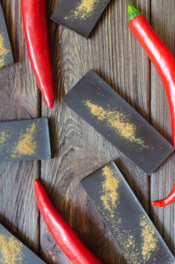 Ahşap bir masada üç kırmızı biberli ekstra koyu çikolata. Trend gıda konsepti. Seçici odaklanma. Dikey oryantasyon. Üst görünüm.