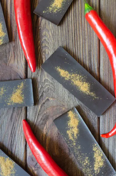 Ahşap bir masada üç kırmızı biberli ekstra koyu çikolata. Trend gıda konsepti. Seçici odaklanma. Dikey oryantasyon. Üst görünüm.