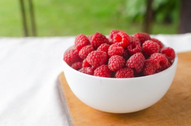 Beyaz arka planda bir kasede olgun pembe ahududular. Yaz çileği hasadı kavramı. Yatay oryantasyon. Seçici odak.