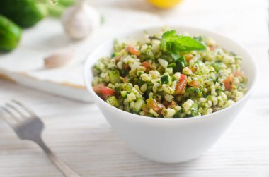 Doğu salatası Tabbouleh, ahşap bir masada beyaz bir kase içinde. Geleneksel Lübnan mutfağı veya Suriye mutfağı kavramı. Vejetaryen ya da vejetaryen yemeği. Seçici odaklanma. Yatay oryantasyon. Boşluğu kopyala