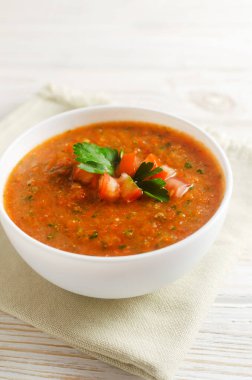 Soğuk yaz çorbası Gazpacho. Masadaki peçetenin üzerinde beyaz bir kâse içinde. Geleneksel İspanyol mutfağı. Vejetaryen ya da vejetaryen. Seçici odaklanma. Dikey yönelim.