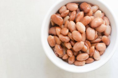 Gri arka planda beyaz bir kasede kaynamış borlotti fasulyesi. İtalyan mutfağı. Vejetaryen ve vejetaryen yemekleri. Seçici odaklanma. Yatay oryantasyon. Uzayı kopyala Üst görünüm