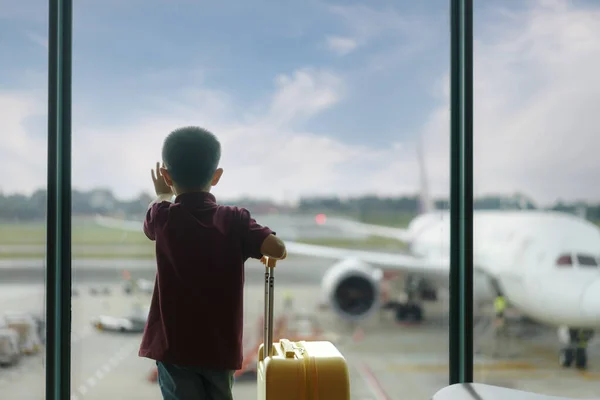 亚洲男孩在空荡荡的机场候机楼等待起飞 望着窗外 穿着T恤和短裤的孩子站在休息室等飞机 家庭旅行概念 — 图库照片
